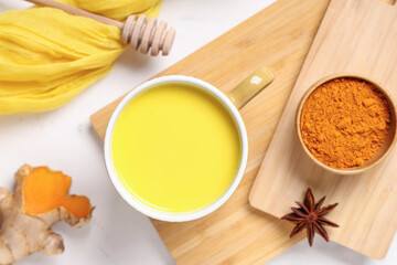 Composition with cutting boards, cup of healthy turmeric drink and ingredients on white grunge background, closeup