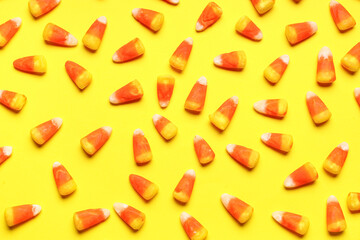 Tasty Halloween candy corns on yellow background, closeup