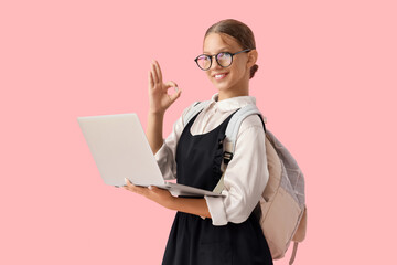 Female student with laptop showing OK on pink background