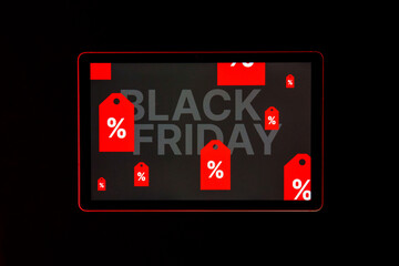 Tablet screen showing black friday text with red percentage discount tags on a dark background