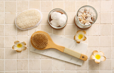 Composition with marble tray, plumeria flowers and massage body brushes on beige tile background, closeup