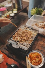 A person stir-frying meat with onions.