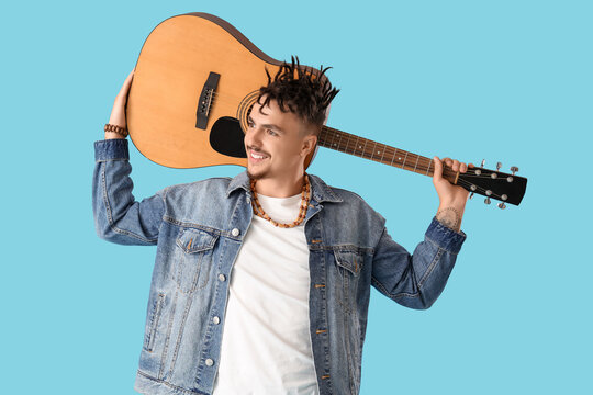 Young man with dreadlocks and guitar on blue background