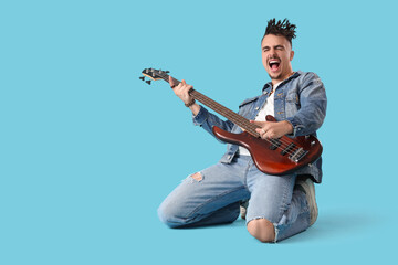 Singing young man with dreadlocks playing electric guitar on blue background