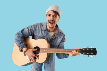 Young man playing guitar on blue background