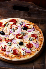 Pizza with salami, jalapeno pepper, cherry tomatoes and mozzarella cheese. Soft focus.	