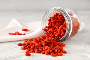 Overturned jar with dried goji berries on white grunge background, closeup