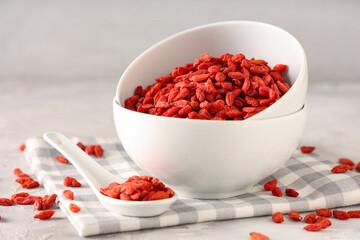 Bowls with dried goji berries on white grunge background, closeup
