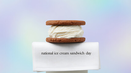 An ice cream sandwich made with two chocolate cookies and vanilla ice cream, displayed on a white pedestal with text celebrating National Ice Cream Sandwich Day.