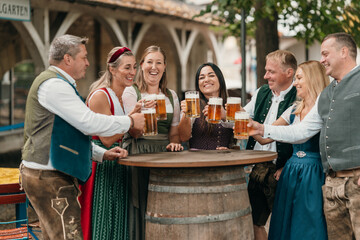 Joyful friends clink beer mugs in Bavarian beer garden enjoying leisure friendship Oktoberfest culture and traditional German celebration