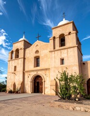 Tan adobe mission church under a vibrant blue sky