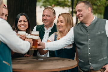 Friends toast with beer mugs in Bavaria enjoying beer garden leisure Oktoberfest tradition German culture friendship and festive celebration