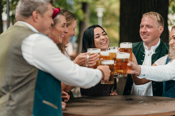 Men and women in Bavaria cheer with beer mugs at beer garden celebrating Oktoberfest friendship leisure German tradition and festive culture
