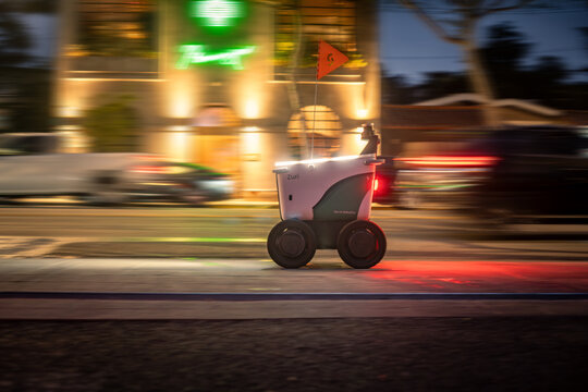 LOS ANGELES, CA - September 25, 2025: Serve Robotics food delivery robot driving along illuminated sidewalk to transport food from restaurants to customers at night in West Hollywood, California.