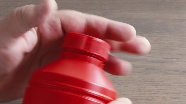 Person closing red container tightly with childproof lid in the kitchen for home chemical safety