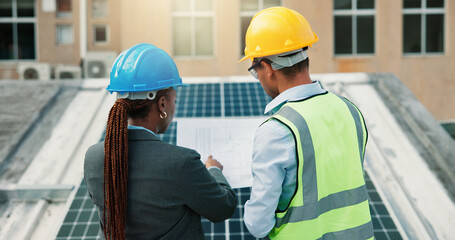 Blueprint, planning and solar energy with construction worker people on roof of building from back. Architecture, collaboration or engineering with team outdoor for installation of photovoltaic panel