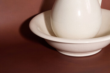 White ceramic pitcher and basin on brown background
