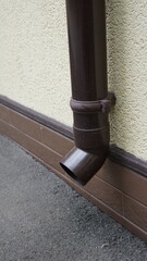 Lower part of plastic drainpipe brown color drainage system on building
