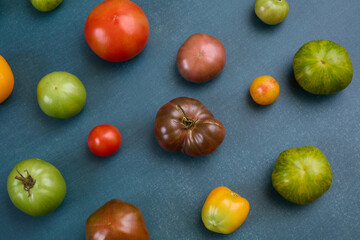 Scattered assorted heirloom tomatoes on blue background
