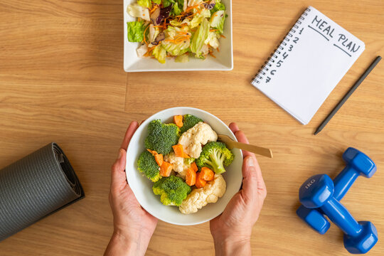 Nutrition plan and healthy eating lifestyle concept with blank weekly diet planner, vegetables, salad, fitness weights and yoga mat for calorie control and balance. - Powered by Adobe