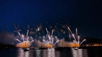 Spectacular fireworks over the harbor with boats silhouetted under the glowing night sky - Powered by Adobe