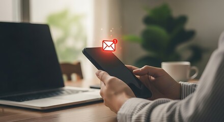 New email notification on mobile phone with laptop and coffee mug