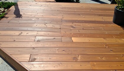 Sunlit wooden deck with parallel planks and green planter—evoking calm, craftsmanship, and the grounded choreography of texture, light, and outdoor design.