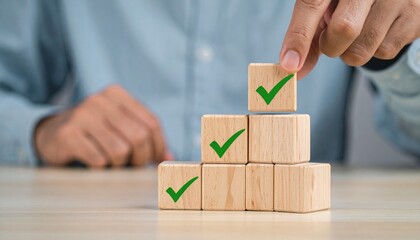 Hand placing top block on pyramid of check-marked blocks—achievement icon and structured form evoke progress, goal completion, and success in minimalist productivity symbolism composition.