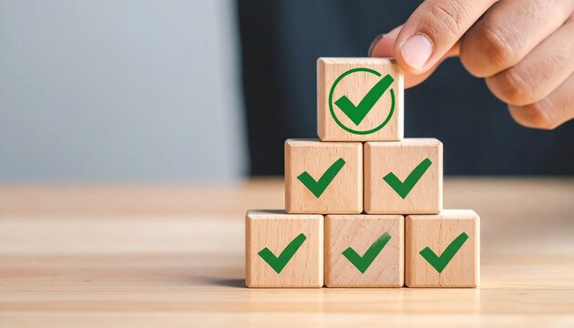 Hand placing top block on pyramid of check-marked blocks—achievement icon and structured form evoke progress, goal completion, and success in minimalist productivity symbolism composition.