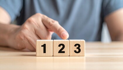 Three numbered wooden blocks—“1”, “2”, “3”—placed side by side with blurred plant in background evoke order, simplicity, and foundational structure in minimalist educational symbolism composition.