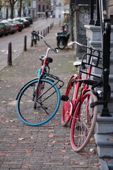 A blue bicycle leans against a railing beside a flower-lined canal in Amsterdam on a sunny day.