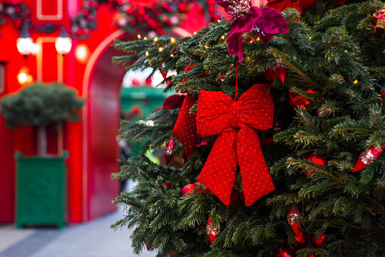 A red bow, gifts, and holiday toys on a Christmas tree in traditional red colors. The concept of preparing and decorating for the New Year. New Year's Eve card 2026.