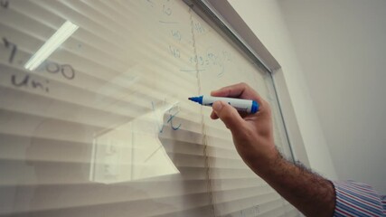 Hand writing mathematical formulas on glass with blue marker during class or meeting. - Powered by Adobe