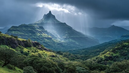 Dramatic mountain vista. Lush valleys and forested slopes ascend to a peak, illuminated by shafts of light piercing a stormy sky