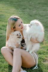 Woman sitting on grass with two Pomeranian dogs