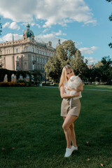 Fototapeta premium Woman holding fluffy Pomeranian in city park