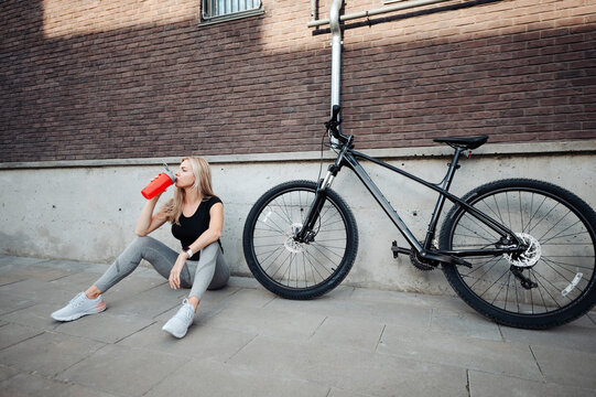 Sporty woman drinking water after outdoors cycling