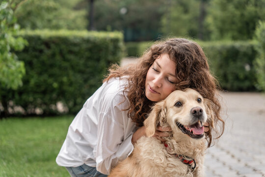 Happy woman hugging golden retriever in park.