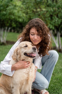 Happy woman hugging golden retriever in park.