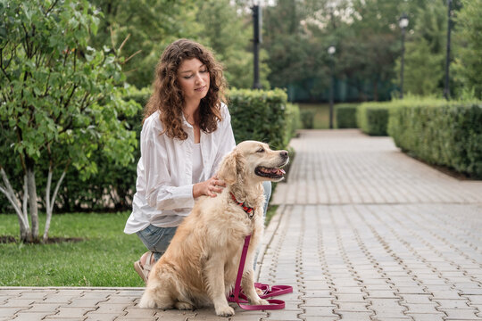 Happy woman hugging golden retriever in park.