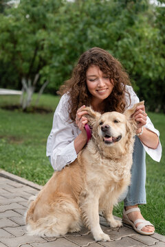 Happy woman hugging golden retriever in park.