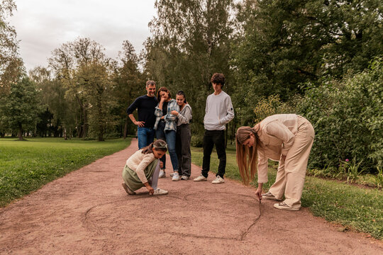 Children draw a big heart on a path in the park.