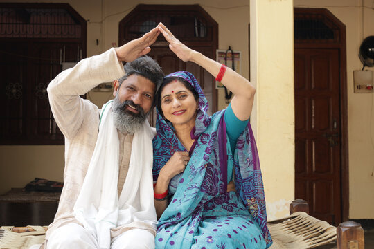 Home Dream. Happy Indian farmer with wife and young daughter making home shape with hand. dream home concept.