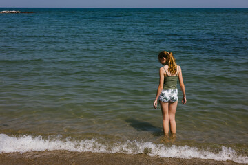 Fototapeta premium Young teen girl in swimsuit on lake shore in full summer sunshine