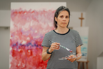 Female artist mixing colors on palette while painting abstract modern art