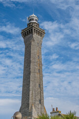 Fototapeta premium Historic Eckmuhl lighthouse, Point Penmarc'h with its 65-meter octagonal Kersanton stone tower. Dramatic sky frame this Breton maritime beacon