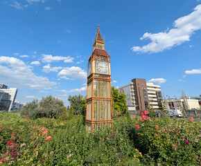 Big Ben tower as a scale model of a building of Houses of Parliament and Westminster pier. An imitation of the exterior of a famous building. A lightweight structure built on a flowerbed.
