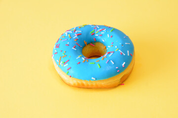 a blue donut with sprinkles isolated on the yellow background