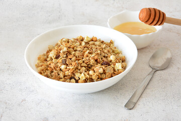 a bowl of healthy granola with a spoon and a bowl of honey