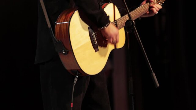 Man playing guitar on music stage in dark, musician, close-up